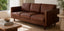 Mid century modern real leather sofa with wooden arm detailing in a living room setting with a coffee table and decorative items.