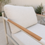A close-up of a modern outdoor patio chair with a light beige cushion, a light gray frame SE Queensland
